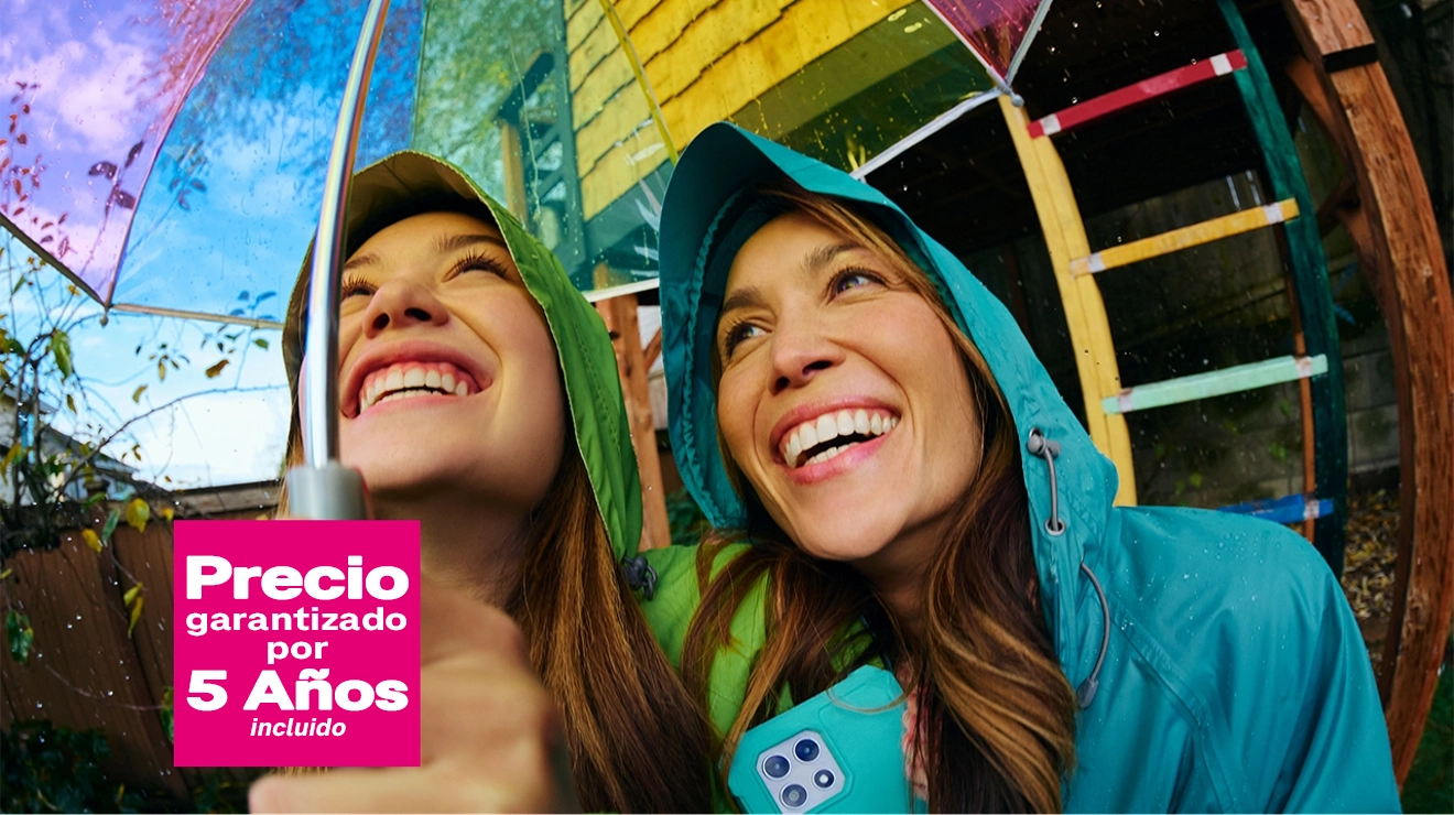 Riendo, dos jóvenes se abrazan bajo un paraguas con las palabras &quot;precio garantizado por cinco años incluido&quot;.